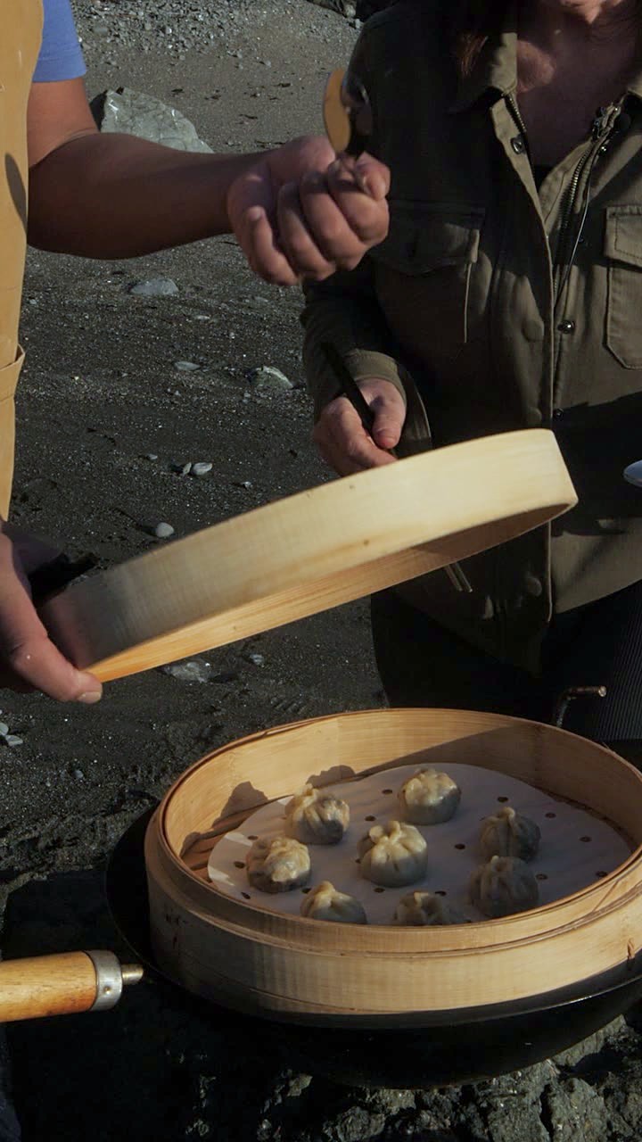 The bamboo steamer lid lifted to reveal dumplings on the beach