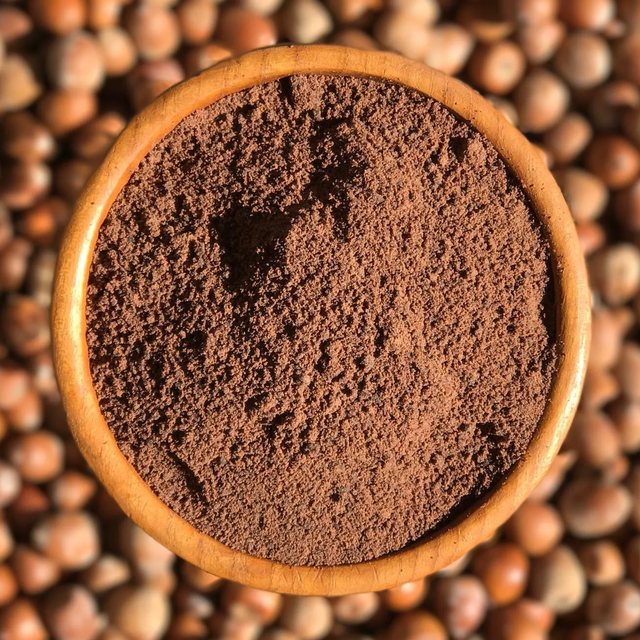 A wooden bowl of acorn flour on a bed of acorns