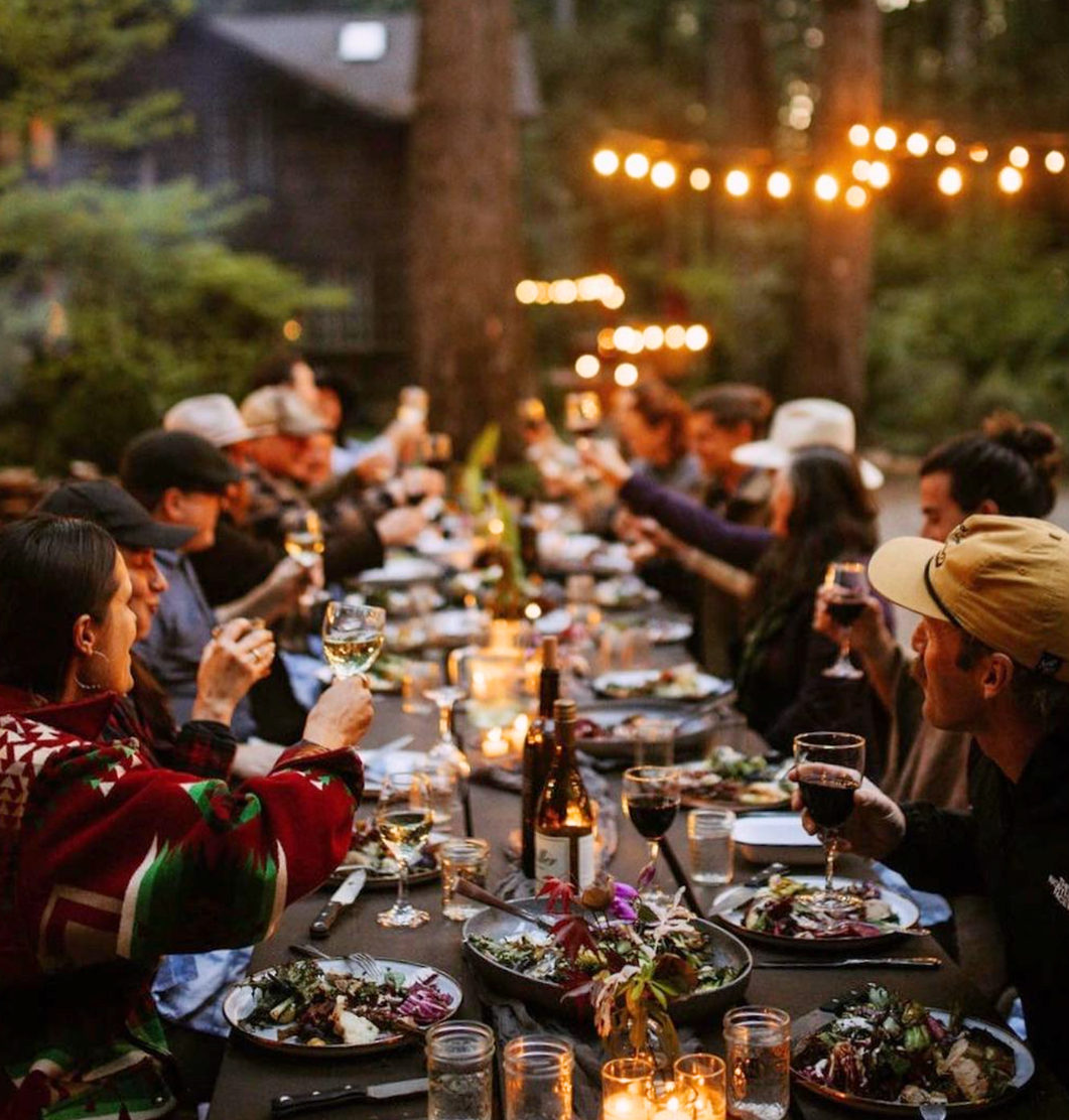A long candlelit dinner table in the forest